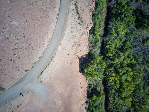 A dirt road in a canyon in Utah. Straight dow view with river and trees to the right - Powered by Adobe