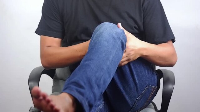 Knee pain, arthritis, joint inflammation, and degenerative changes. A man suffering from leg pain performs a self-massage at home. It focuses on joint care, relaxation, and alleviating knee pain or of