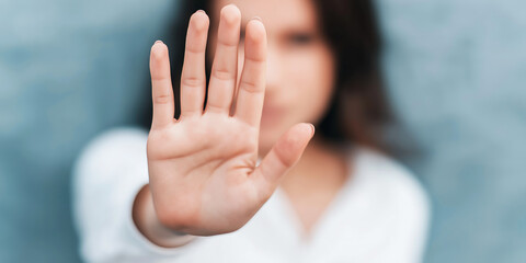 Woman's hand raised, palm facing out, signaling stop, refusal, and setting limits against unwanted advances or conditions