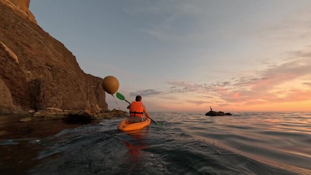 Kayaker ocean sunset paddling along rocky coast at golden hour, peaceful sea adventure at dawn - Powered by Adobe