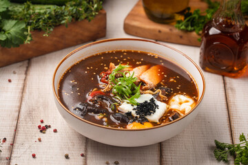 Spicy Korean ramen soup with egg, seafood, mushrooms and fresh scallions served in a ceramic bowl