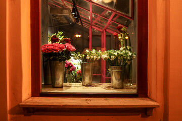 Flowers in window display at a florist shop with a warm, inviting atmosphere