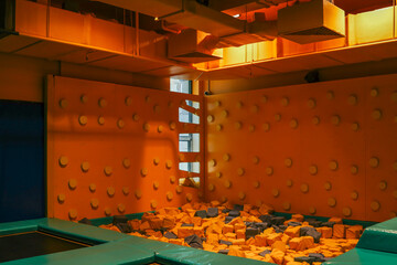 Indoor trampoline park with foam pit and orange and yellow walls