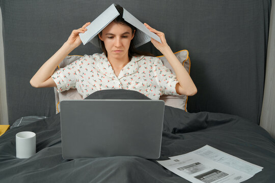 Woman working with laptop and documents in bed