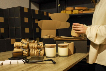 Woman packaging candles in a workshop, ready for shipping and delivery