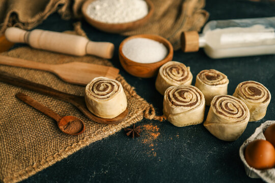 Freshly baked cinnamon rolls with ingredients on a rustic dark background - Powered by Adobe