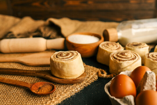 Freshly made cinnamon rolls with ingredients on a rustic wooden table