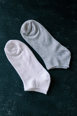 Pair of white and gray socks on a dark green textured background