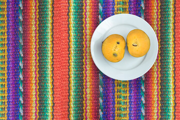  fresh lucuma or eggfuits on a Colorful background of traditional textile fabric, Peru, Latin America