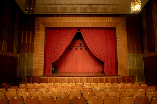 an old empty theater auditorium with seats and a dimly lit stage