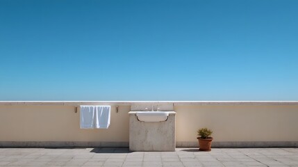 Fototapeta premium A minimalist outdoor sink and towel rack on a sun drenched balcony against a vast clear blue sky