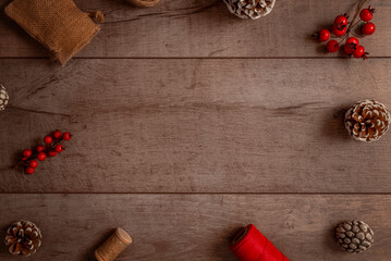 Wide Christmas background with rustic wood surface, berries, cones and festive elements, ideal for advertisements, greeting cards, product placements and winter promotions