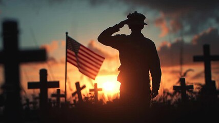 Silhouette of a soldier saluting the American flag at sunset in a military cemetery.