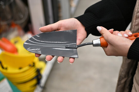 Person holds a gardening tool in a store while shopping for supplies in fall