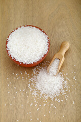 White sugar spilled out of clay bowl and wooden scoop