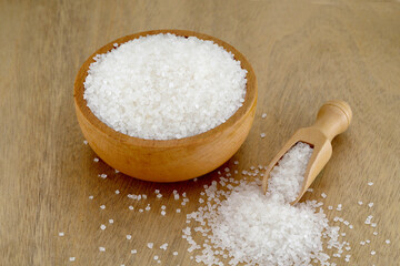White sugar spilled out of  wooden bowl and scoop