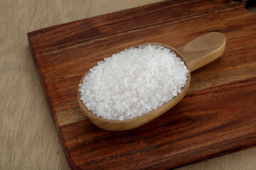 White sugar spilled out of wooden scoop