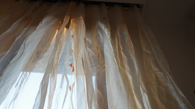 Warm sunset glow. Time lapse captures peaceful transition of daylight to dusk through the window, creating a serene atmosphere. The movement of sunrays can be seen on orange transparent curtains.