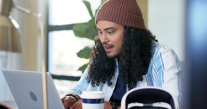 Software developer surveying laptop screen typing code to focus while sipping coffee at desk