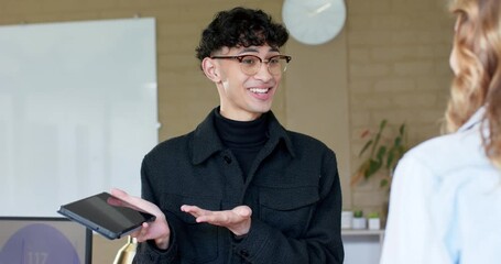 Raising tablet, male presenter showing tablet features to female colleague in office