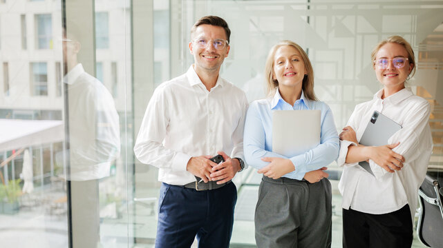 Three professionals pose in a modern office space