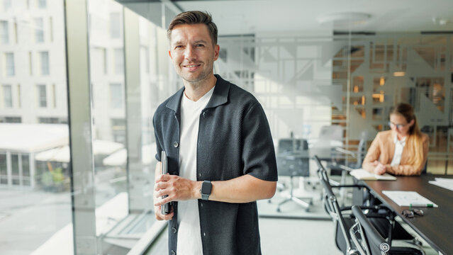 Man standing with a notebook in a modern office space - Powered by Adobe