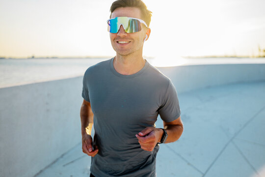 Man jogging by the waterfront in sporty attire - Powered by Adobe