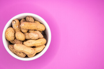 Monkey nuts in white dish on plain background
