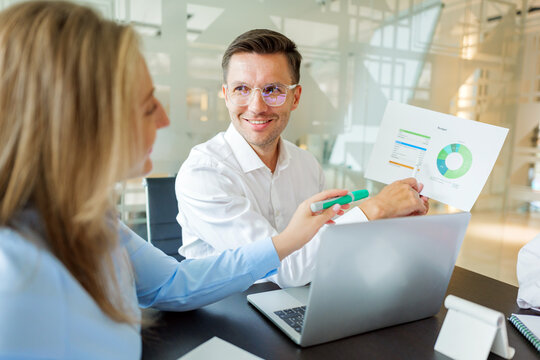 Smiling man presents data during business meeting
