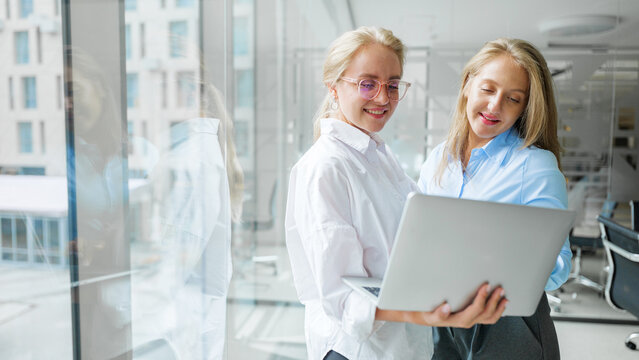Women collaborating on a laptop in a modern office - Powered by Adobe