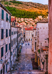 Cobblestone street in Dubrovnik Old Town with Mount Srd at golden sunset, Croatia