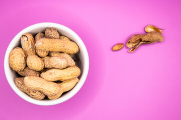Monkey nuts in white dish on plain background