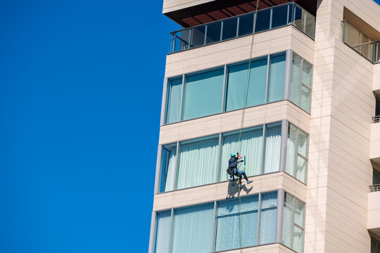 Window cleaners works on high rise building against blue sky, Fukuoka, Japan.  Window cleaning is considered one of the most dangerous job in the world