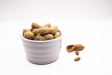 Monkey nuts in white dish on plain background