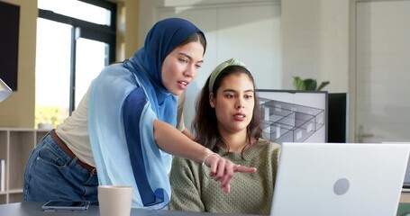 Diverse coworkers approaching desk leaning over laptop guiding through floor plan in modern office - Powered by Adobe