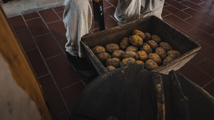 Obraz premium Wooden Box Full of Dirty Potatoes, Scenography Detail with the Figure of a Soldier in Uniform in the Historic Kitchen