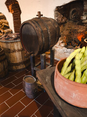 Large Wooden Barrel on a Tall Stand in a Historic Interior with a Dark Brick Fireplace, Antique Pots and a Clock on a White Wall