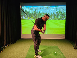 Golfer practicing swing technique indoors at virtual driving range