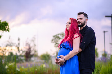 A couple stands outdoors among greenery as the man gently holds his pregnant partner’s belly. A calm, intimate moment of expecting a baby, filled with love and connection