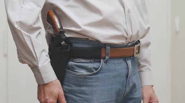 Detail of human with handgun indoor at home drawing his weapon
