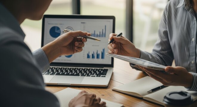 Business professionals reviewing financial charts on a laptop during a meeting