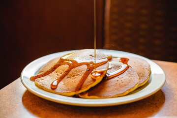 Pancake with syrup being drizzled on top at a breakfast food restaurant