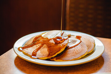 Pancake with syrup being drizzled on top at a breakfast food restaurant