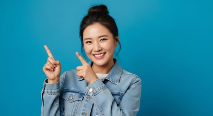 Cheerful Asian woman with a bright smile pointing upwards creating an inviting atmosphere perfect for announcements, promotions, and optimistic messages
