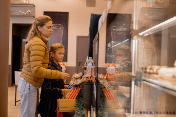 Mother and daughter ordering coffee at a café counter, choosing drinks together. Warm daily moment, modern family lifestyle and casual coffee shop atmosphere.
