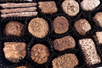 A full box of delicious chocolates. Various chocolate candies in the box closeup