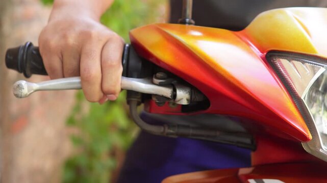 A person's hand pulling and releasing the motorcycle hand brake. Does not show the face.