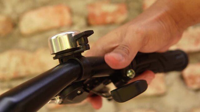 A person's thumb pressing the bicycle bell. Does not show the face.