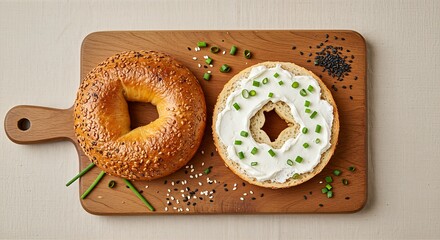 Close-up shot of a sesame bagel next to a bagel with cream cheese and chives on a wooden board.