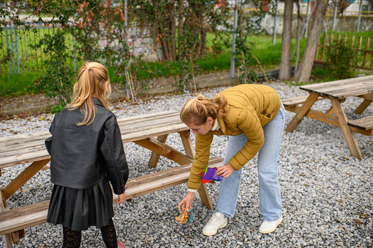 Mother and daughter picking up litter in a public park, collecting trash in bags as part of a community clean-up, promoting environmental awareness and sustainable family activities.